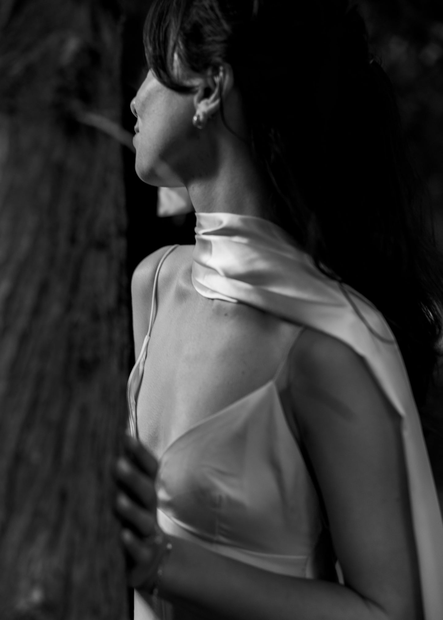Black and white photo of a person wearing a light-colored dress with a draped fabric over one shoulder.