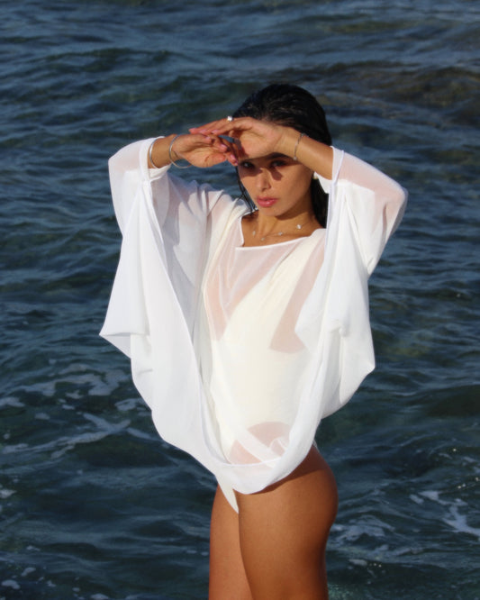 Person wearing a sheer white cover-up by the ocean