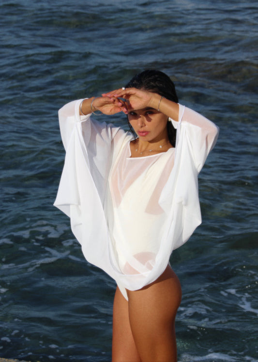 Person wearing a sheer white cover-up by the ocean