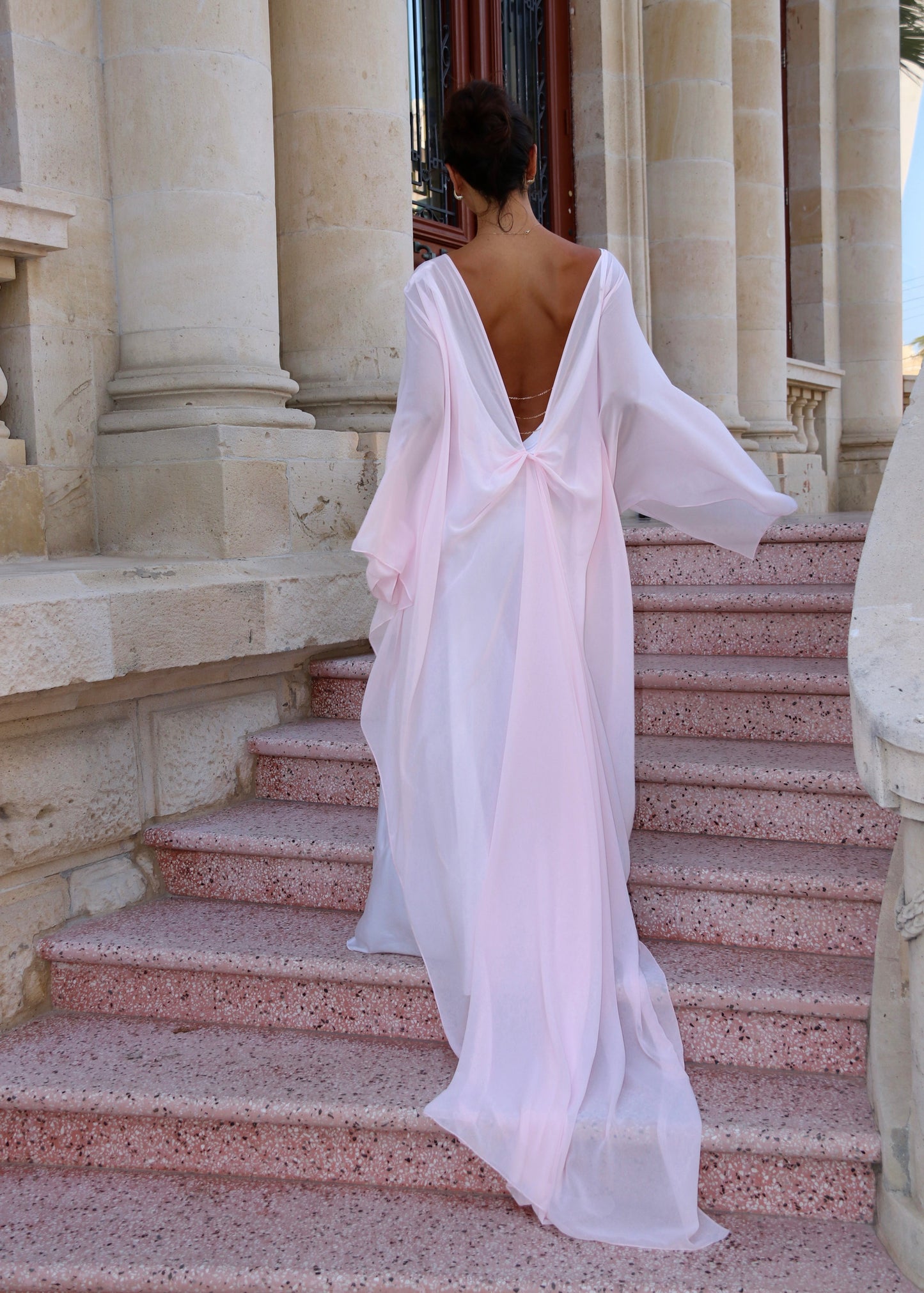women wearing pink Delfino Cape on steps