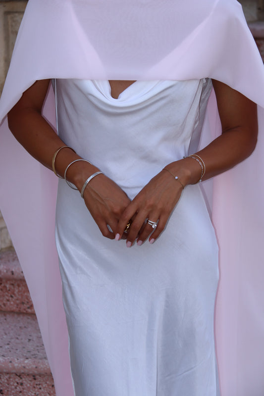 Person wearing a white dress with a pink neck scarf
